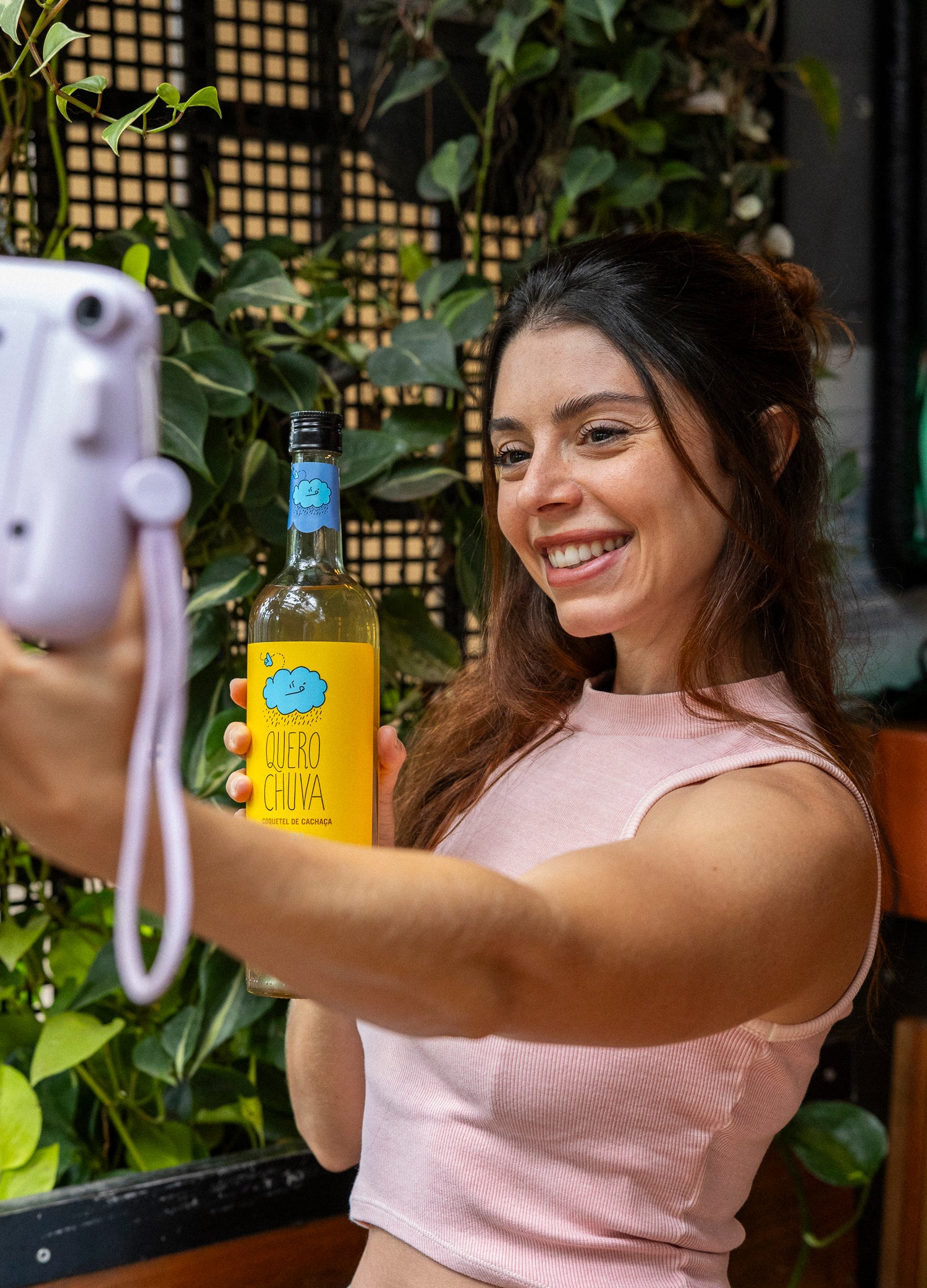 Pessoa tirando selfie ao lado da garrafa Quero Chuva Mel 750 ml