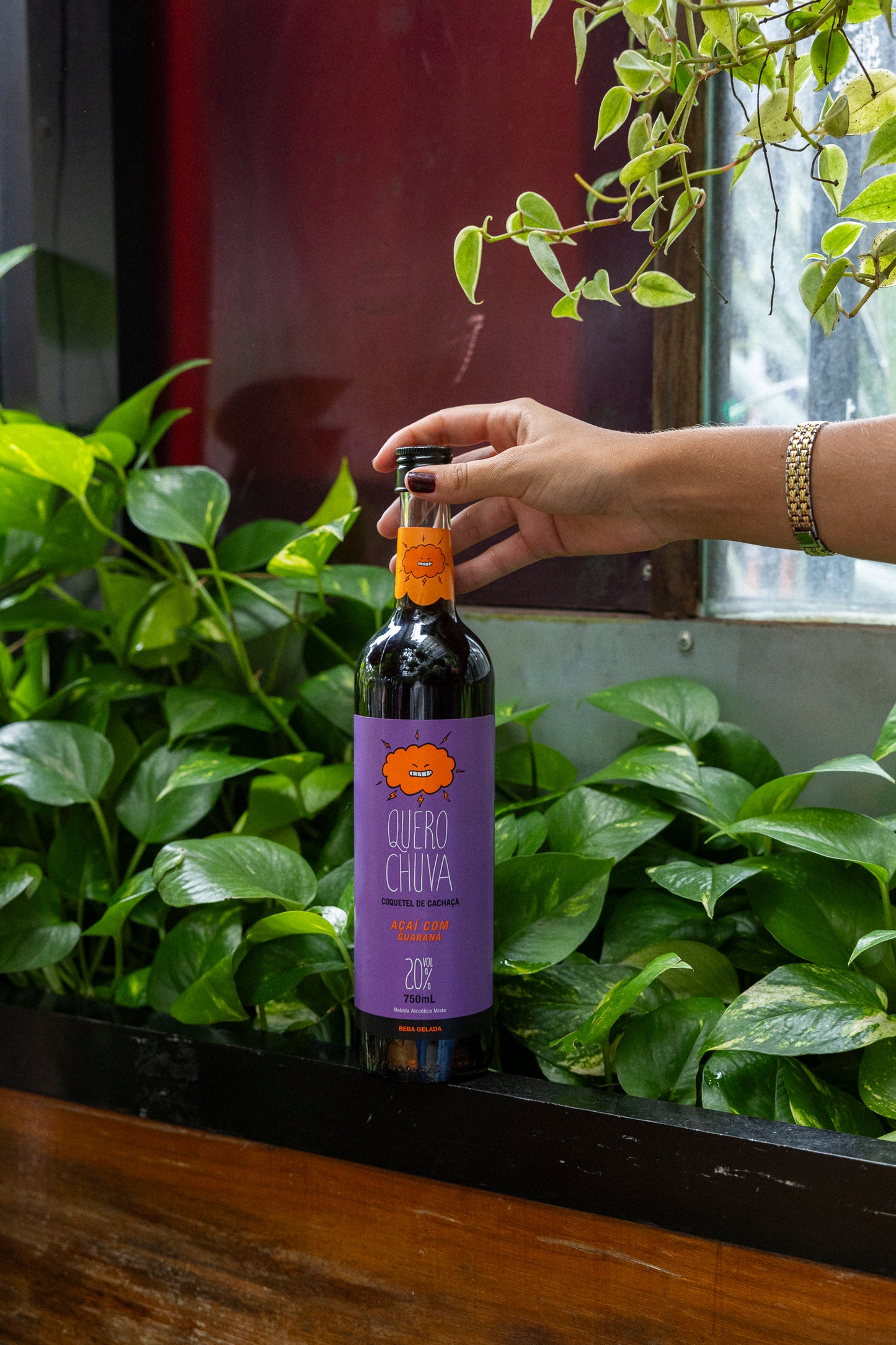 Mão servindo Quero Chuva Açaí com Guaraná no copo entre folhas verdes