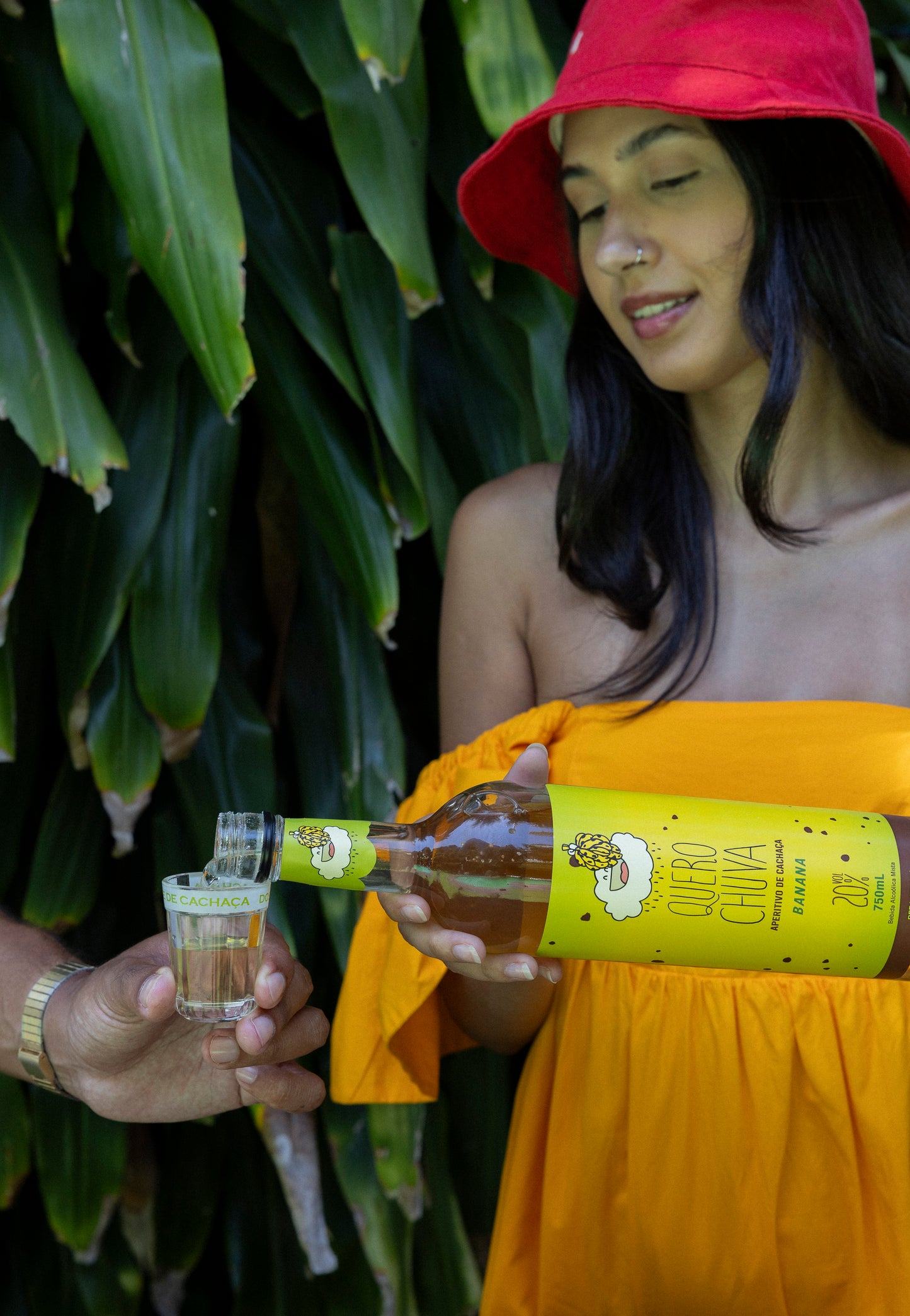Quero Chuva Banana — mulher de chapéu vermelho servindo no copo