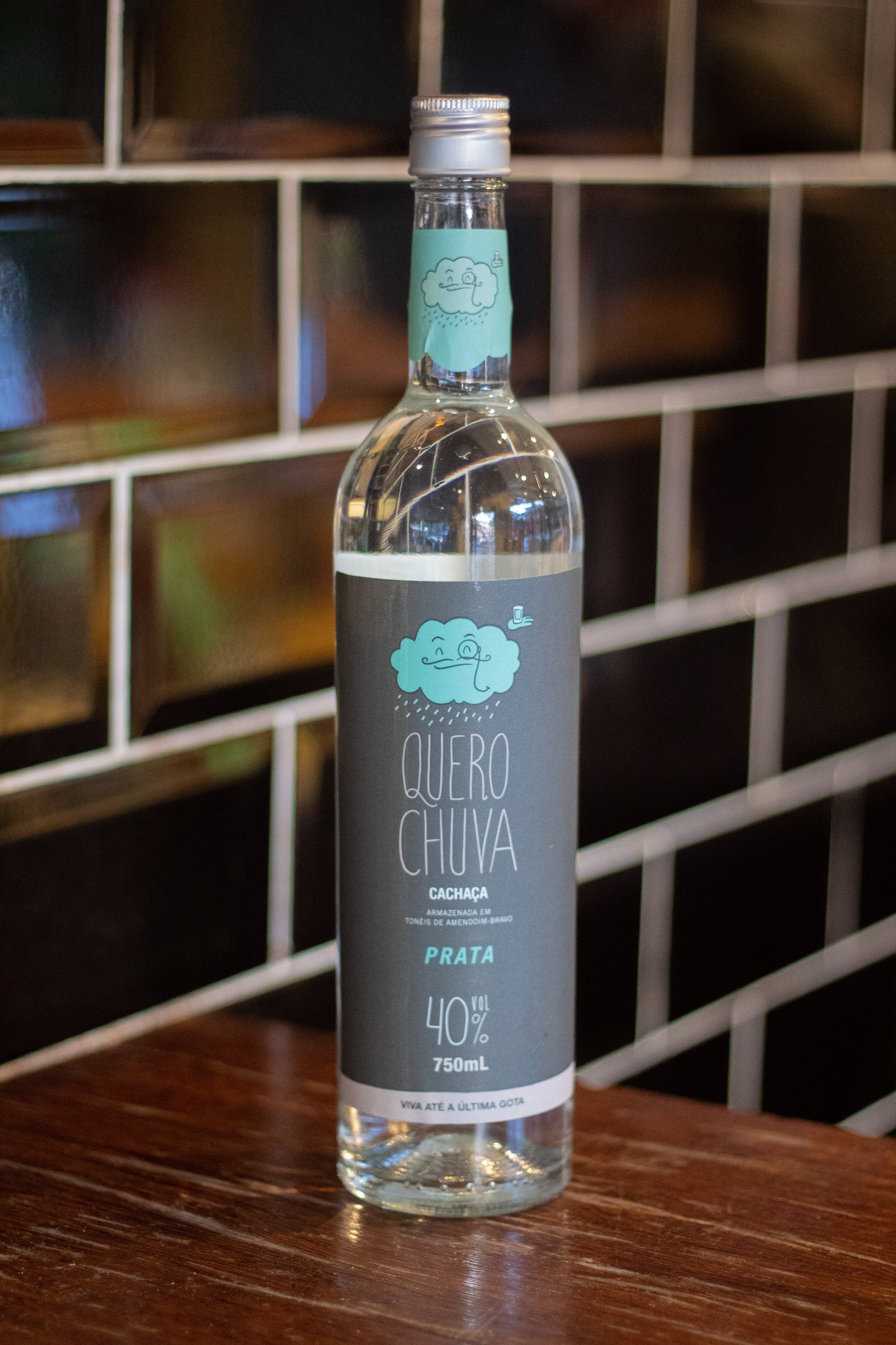 Quero Chuva Prata 750 ml em frente à parede de tijolos