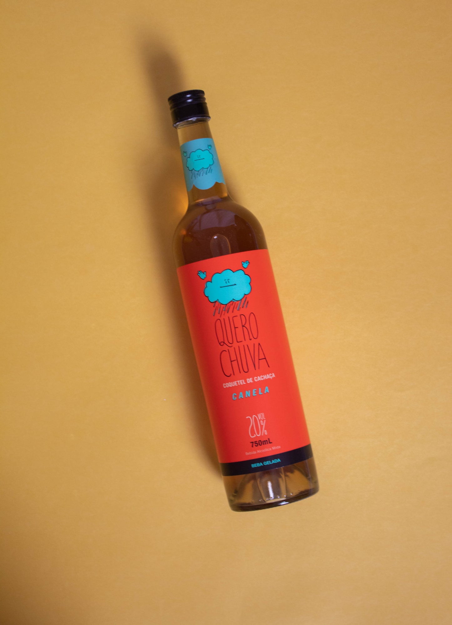 Garrafa Quero Chuva Canela 750 ml deitada em fundo areia — rótulo em destaque