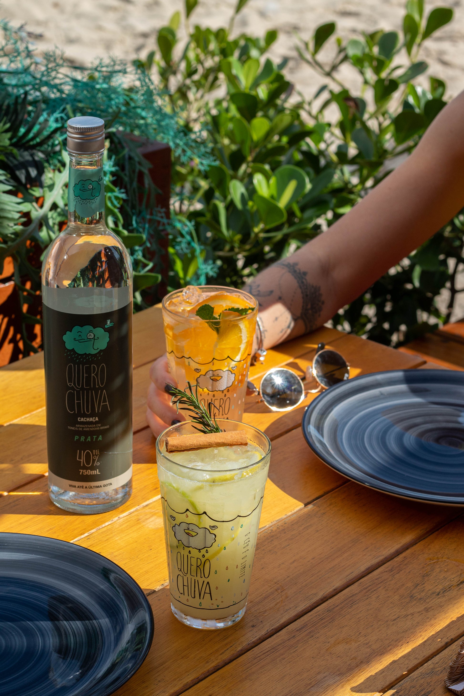 Quero Chuva Prata 750 ml ao ar livre com drinks cítricos na mesa